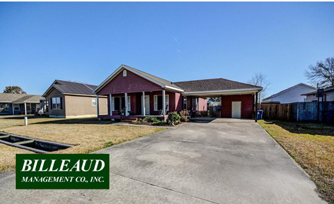 a home with a paved driveway and a red house