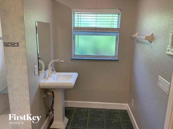 A bathroom with a sink, mirror, and a window.