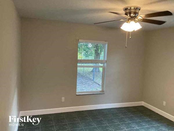 A room with a ceiling fan and a window showing a backyard.