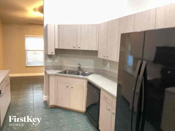 A kitchen with a sink, cabinets, and a refrigerator.