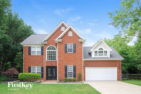 A brick house with a black door and windows is for sale.
