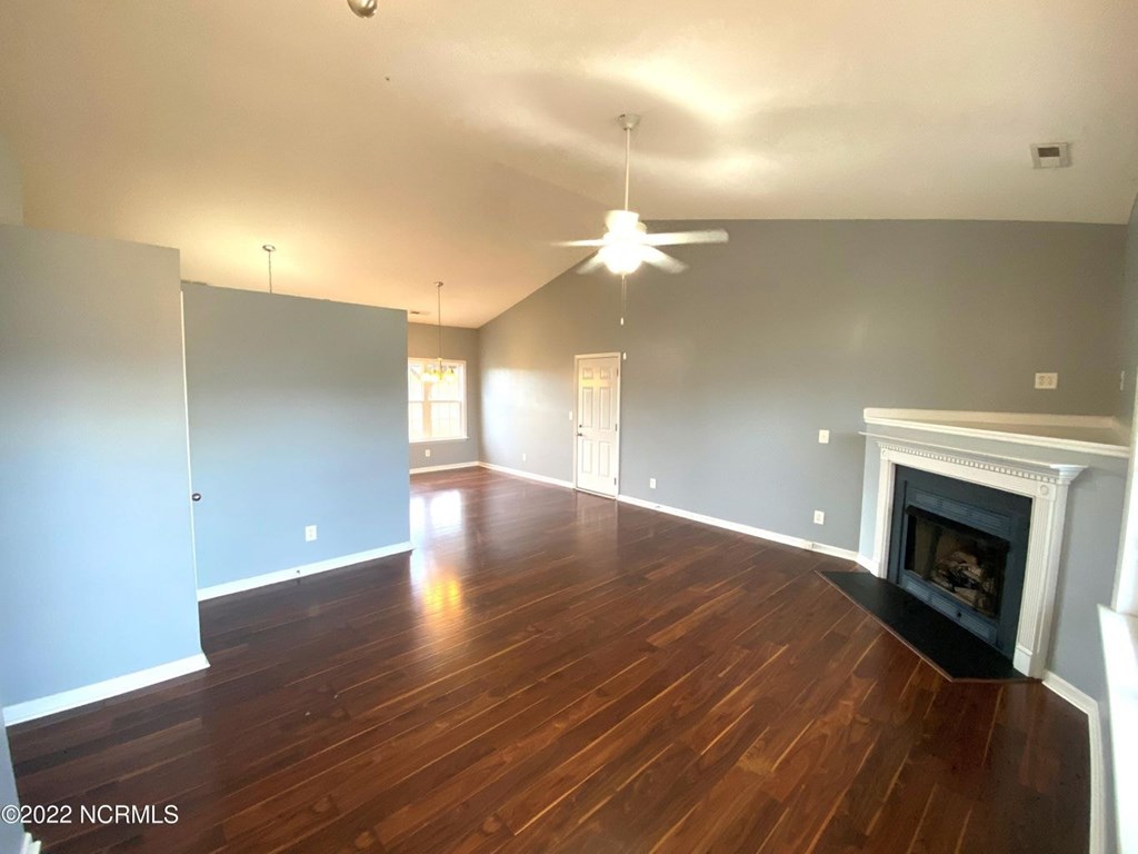 A living room with wood floors and a fireplace.