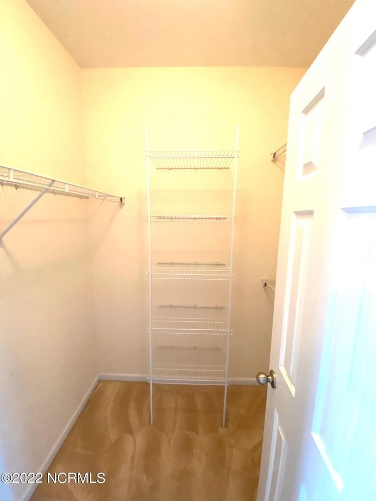 A white closet with a shelf and a door.