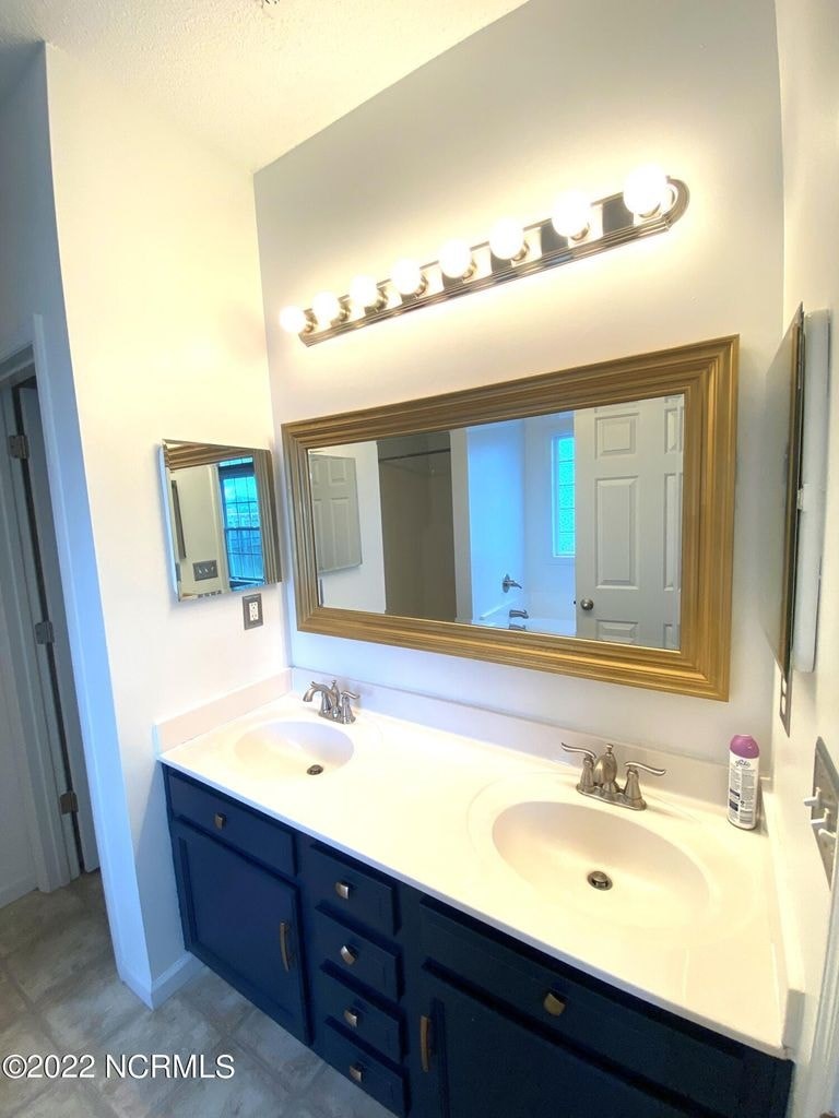 A bathroom with a sink, mirror and light.