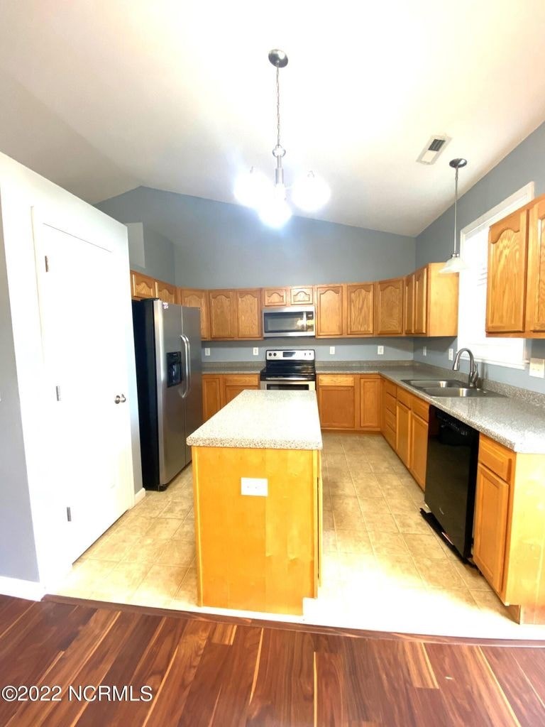 A kitchen with wooden cabinets and a black fridge.