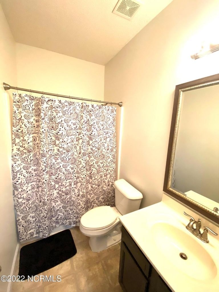 A bathroom with a floral shower curtain and a toilet paper roll on the toilet.