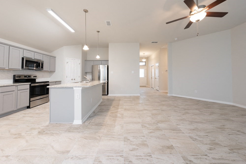 an empty kitchen and living room with a ceiling fan