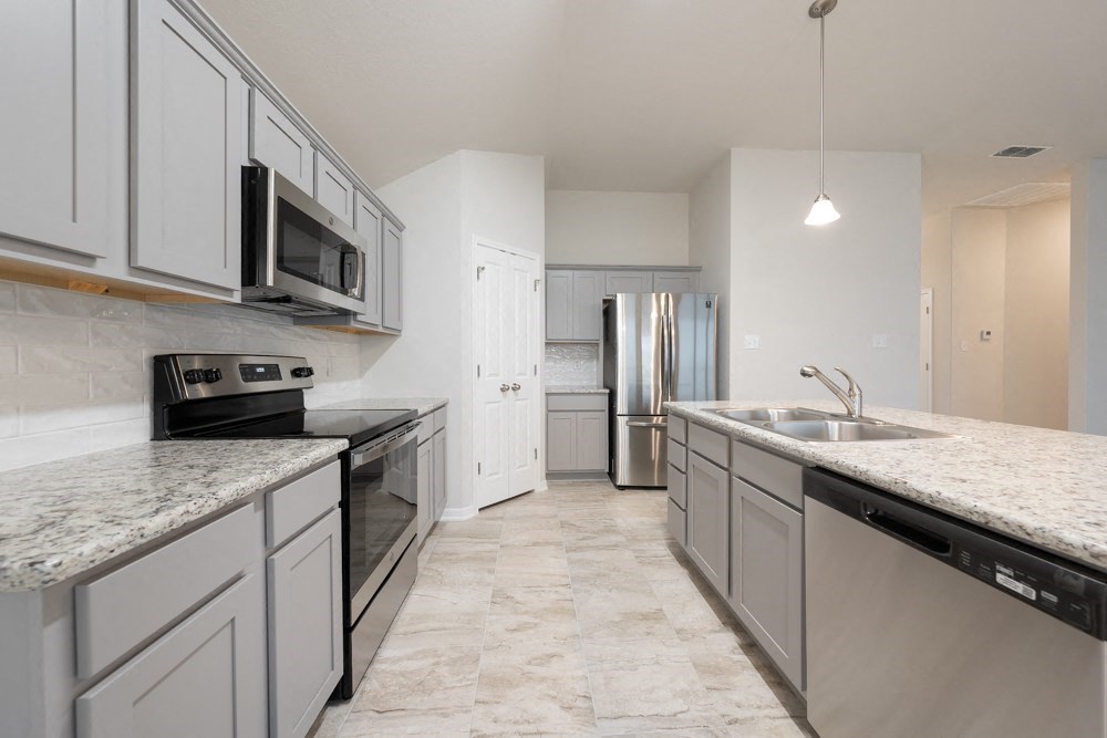 an empty kitchen with stainless steel appliances and marble counter tops