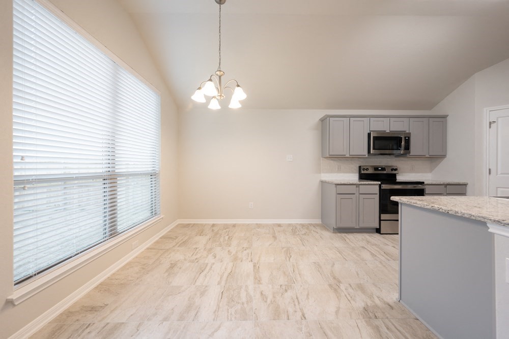 an empty living room with a large window and a kitchen