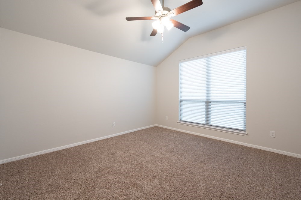 an empty living room with a ceiling fan and a window