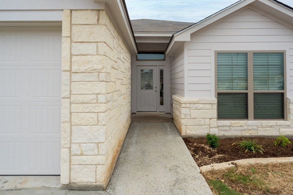 a walkway leading to a house with a white garage door