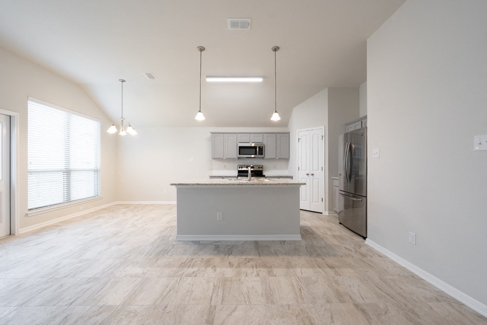 an empty kitchen and living room with a marble counter top