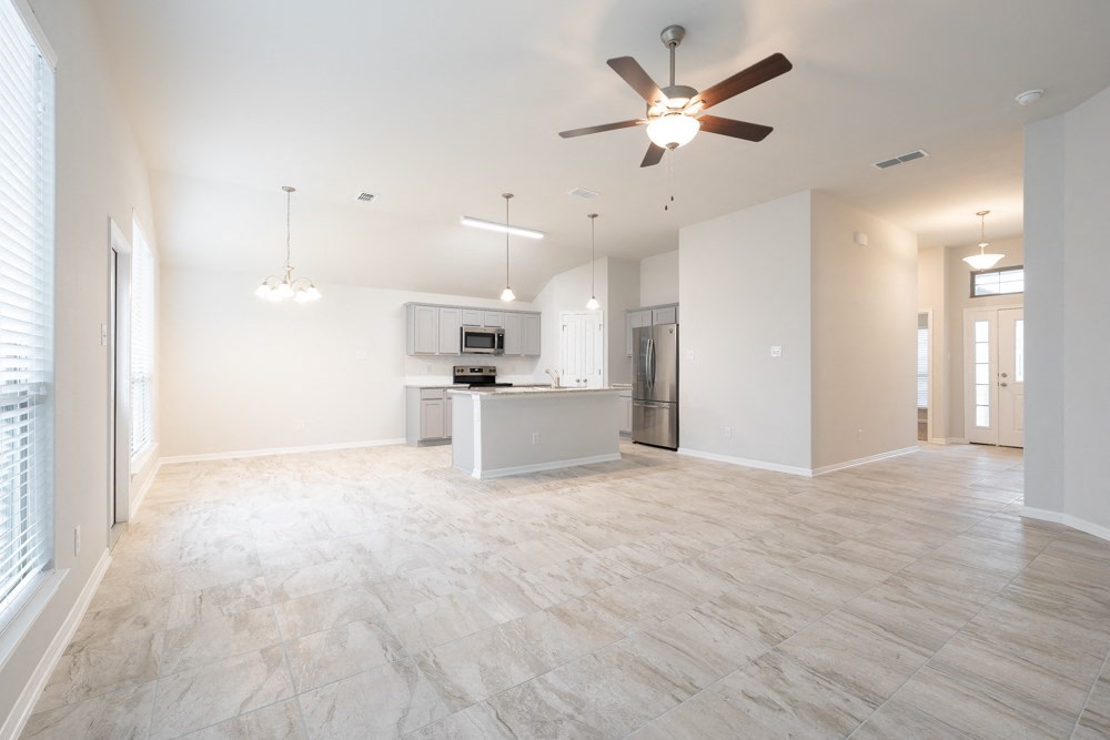 an empty living room and kitchen with a ceiling fan