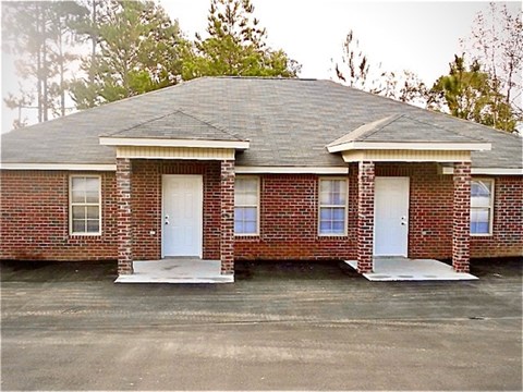 A small brick house with a white door and windows.