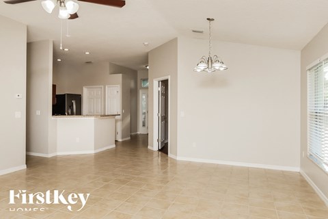 A spacious room with a kitchen area and a ceiling fan.