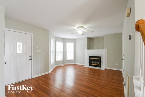 an empty living room with a fireplace and a ceiling fan