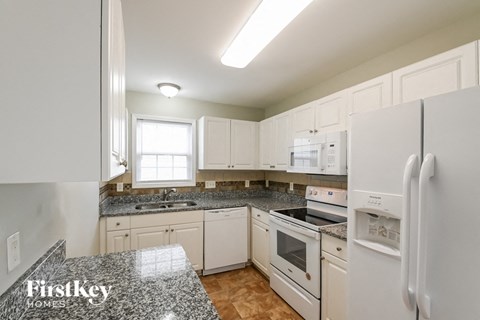a white kitchen with granite counter tops and white appliances