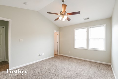 the spacious living room with ceiling fan and carpeting