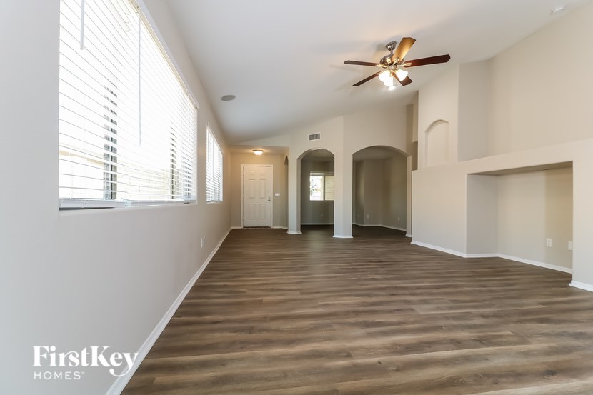 A spacious room with wooden floors and a ceiling fan.
