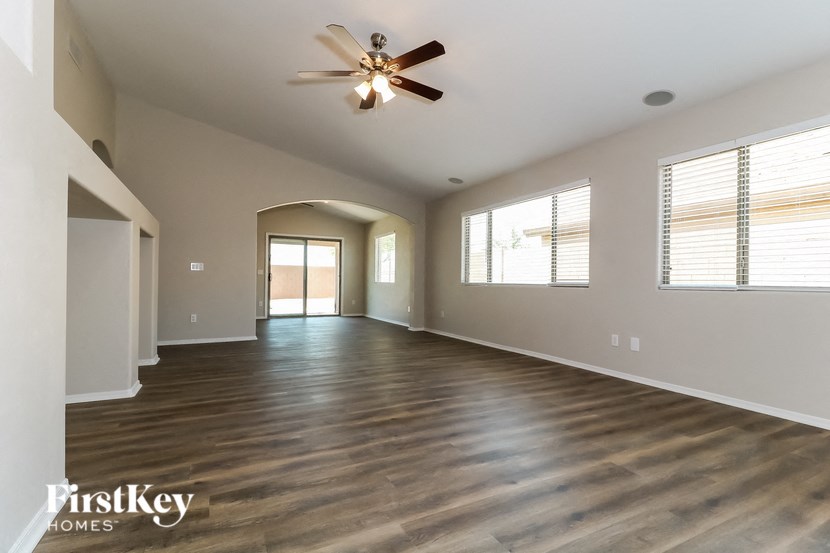 A spacious room with wooden floors and a ceiling fan.