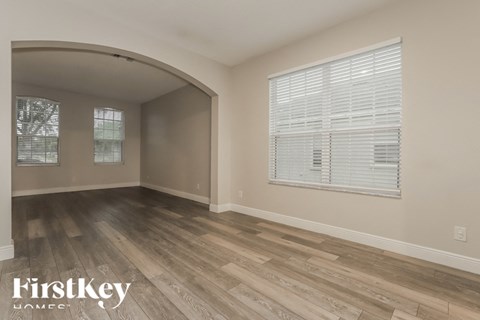 the living room of a home with wood flooring and a large window