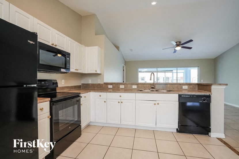 a kitchen with white cabinets and black appliances