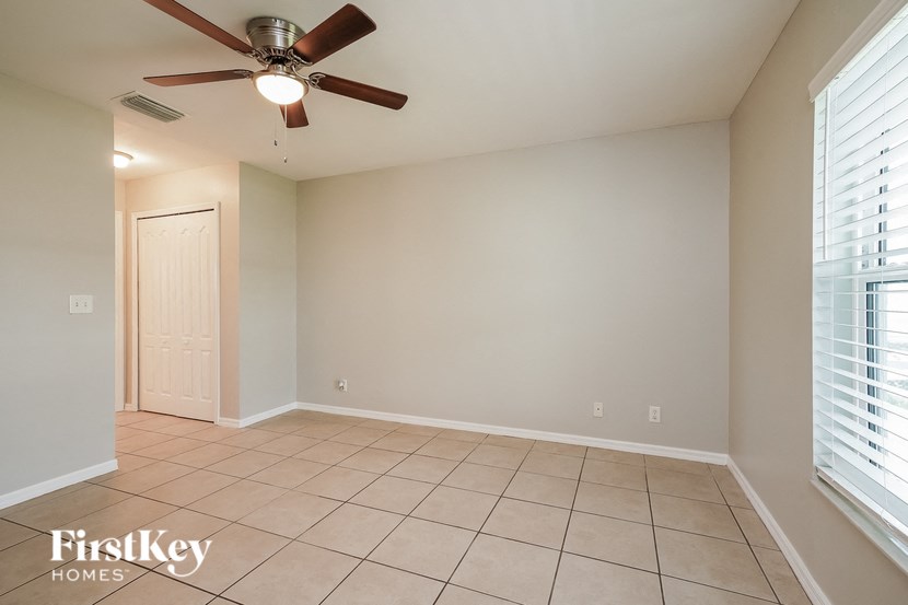 an empty living room with a ceiling fan and tiled floors