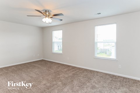 the living room of a home with carpet and a ceiling fan