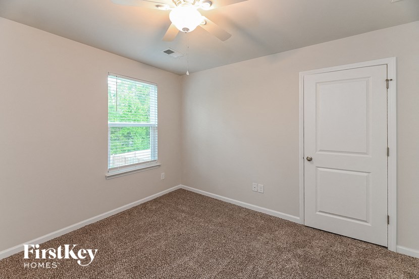 the bedroom of a house with a white door and carpet