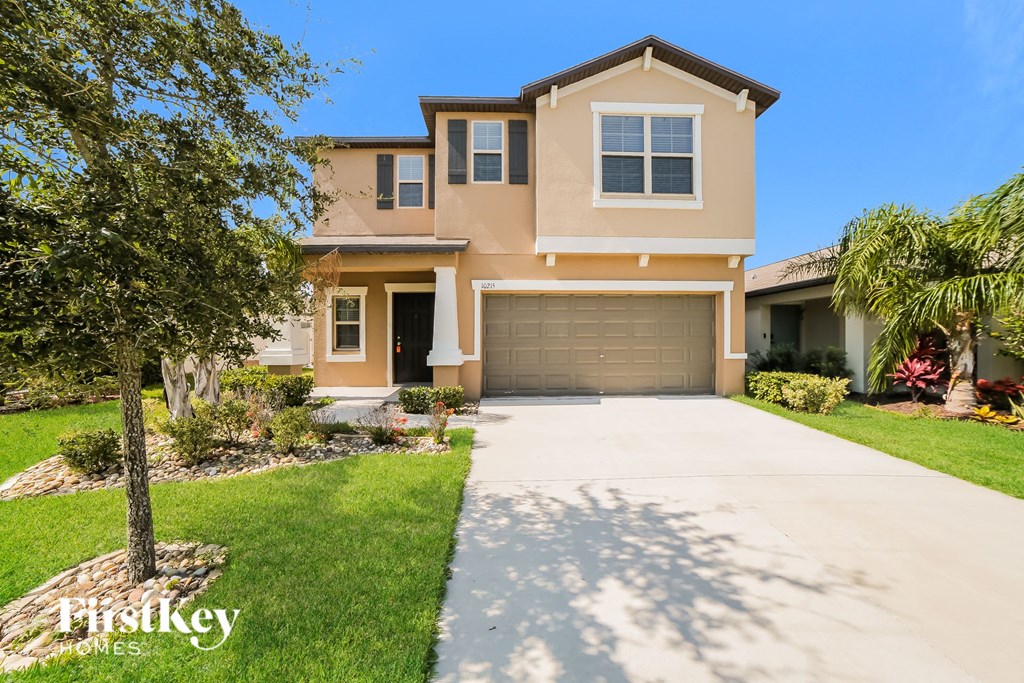 A house with a garage and a driveway in front of it.
