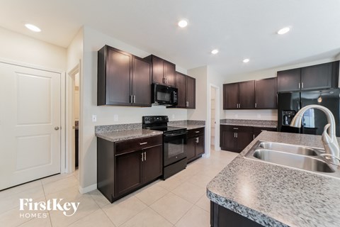 A kitchen with dark brown cabinets and a granite countertop.