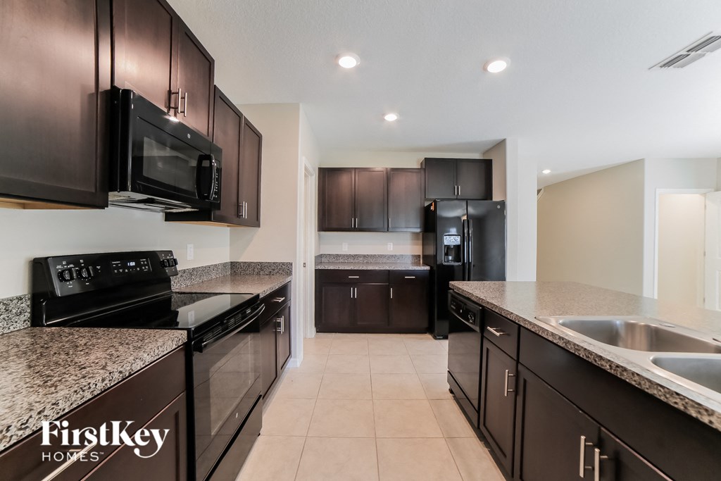 A kitchen with dark brown cabinets and black appliances.