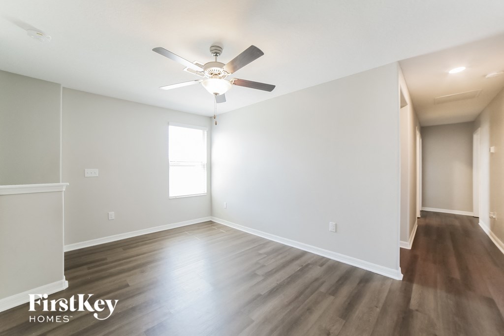 A spacious room with a ceiling fan and wooden flooring.