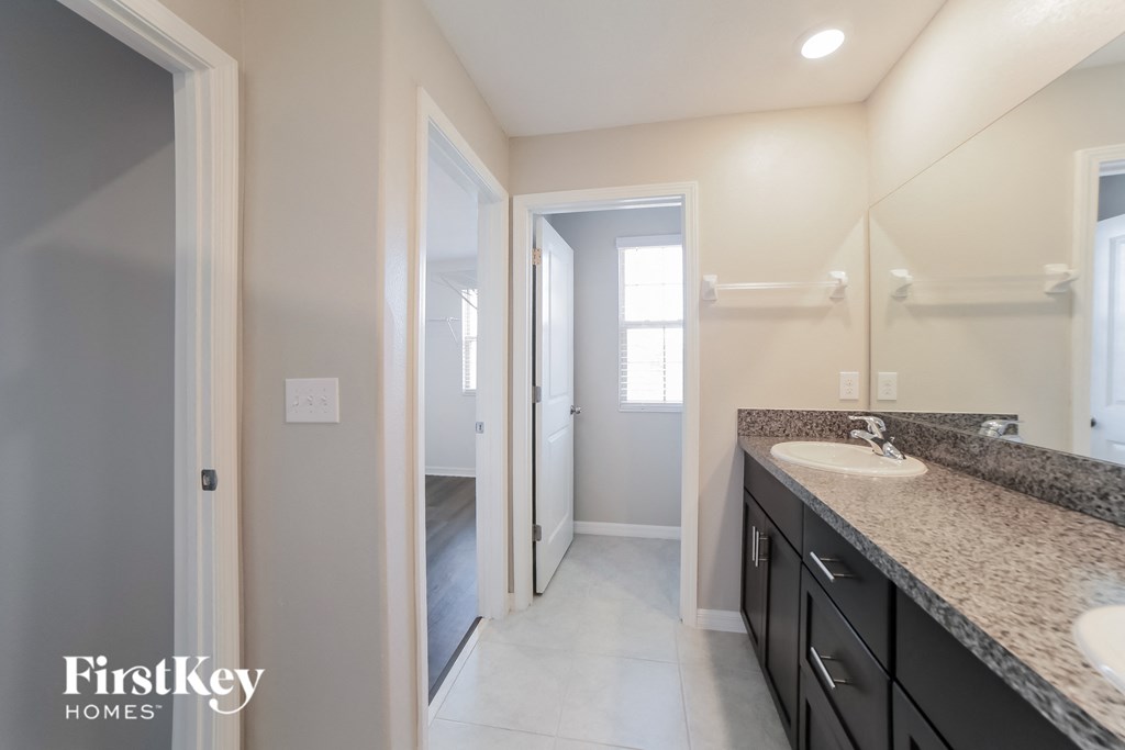 A bathroom with a sink, mirror, and a door.