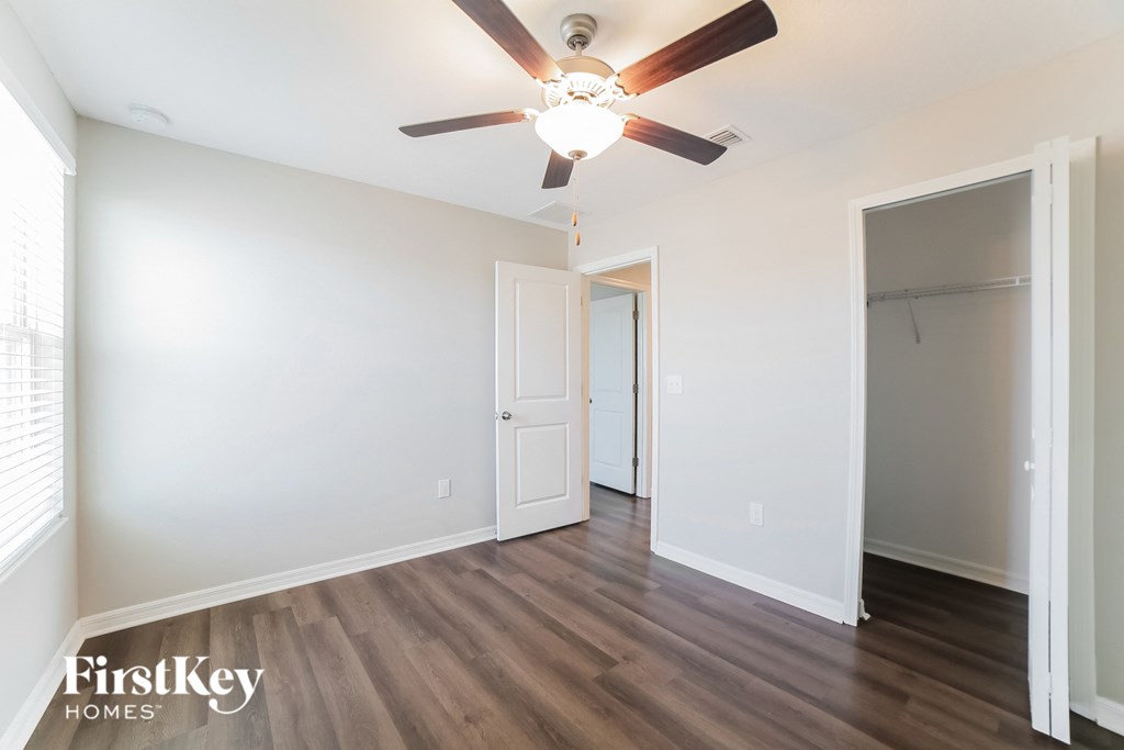 A room with a ceiling fan and wooden flooring.