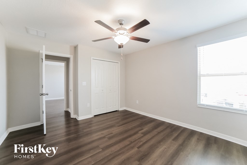 A room with a ceiling fan and wooden flooring.