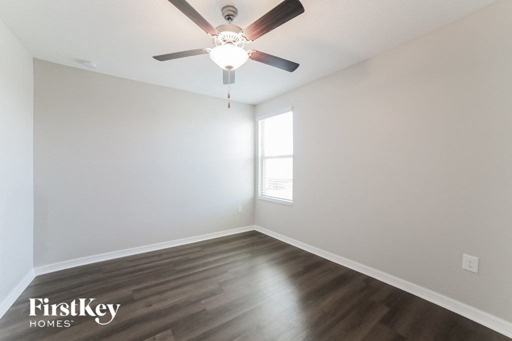 A room with a ceiling fan and wooden flooring.