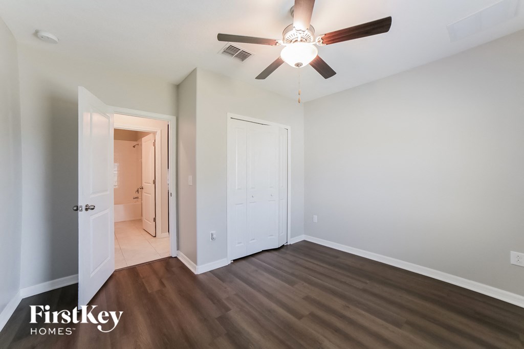 A room with a ceiling fan and wooden flooring.