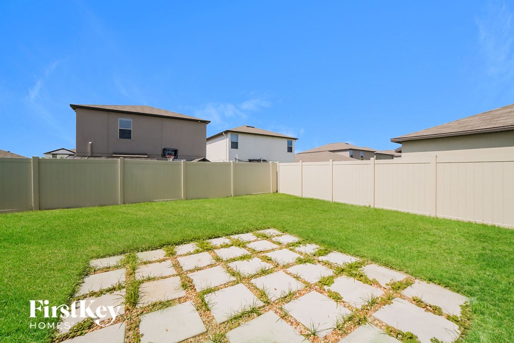 A backyard with a white picket fence and a small garden in the middle.