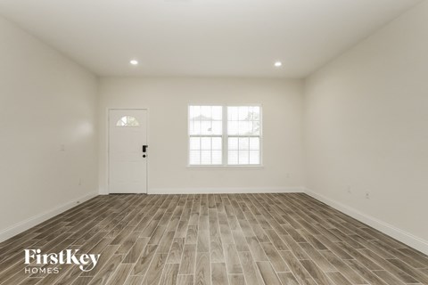 the spacious living room with wood flooring and a white door