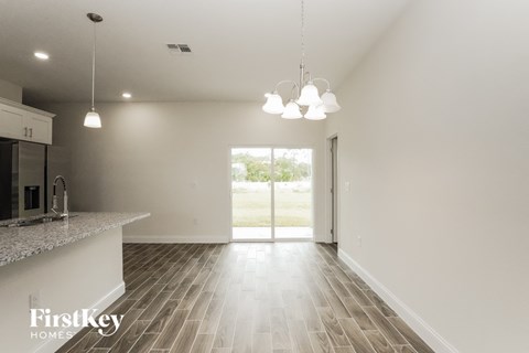 an empty kitchen and living room with white walls and wood flooring
