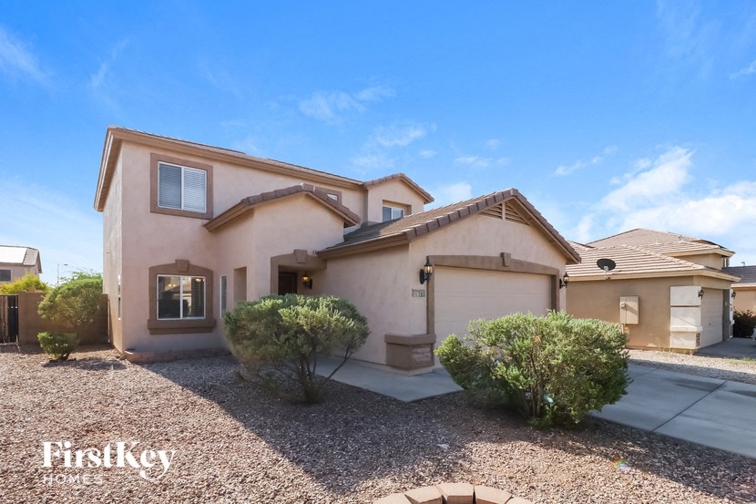A house with a brown roof and a gravel driveway in front of it.