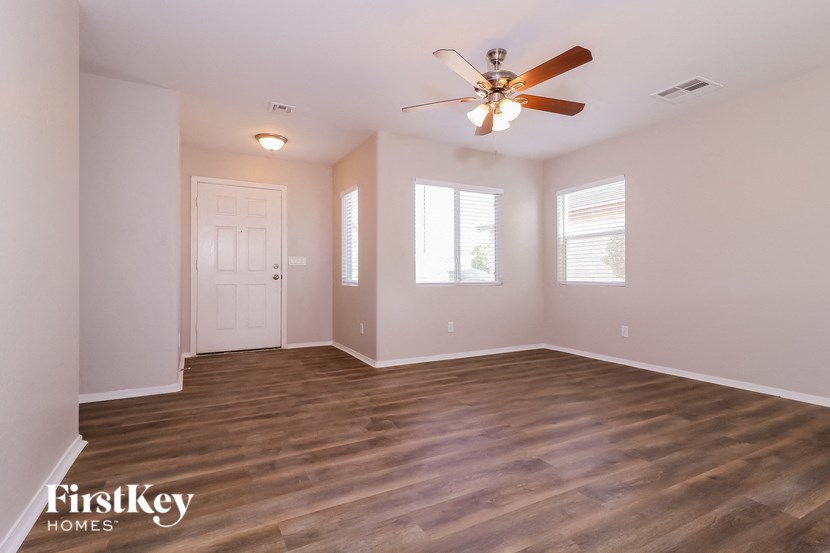 A spacious room with wooden flooring and a ceiling fan.