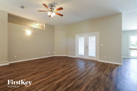 the spacious living room with hardwood flooring and a ceiling fan