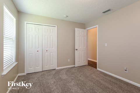 a bedroom with two closets and a carpeted floor and two doors