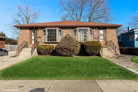 the front of a brick house with a lawn