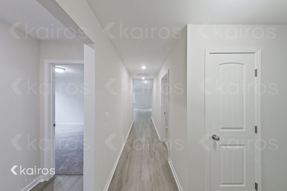 a renovated hallway with white doors and a wood floor