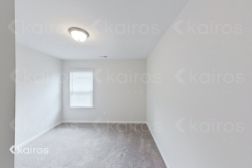 an empty bedroom with white walls and a window