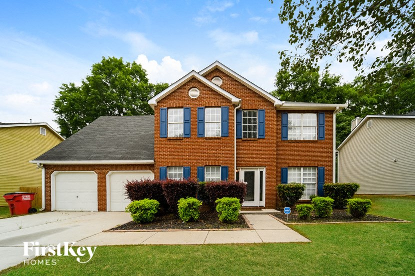 the front of a brick house with a lawn and a driveway