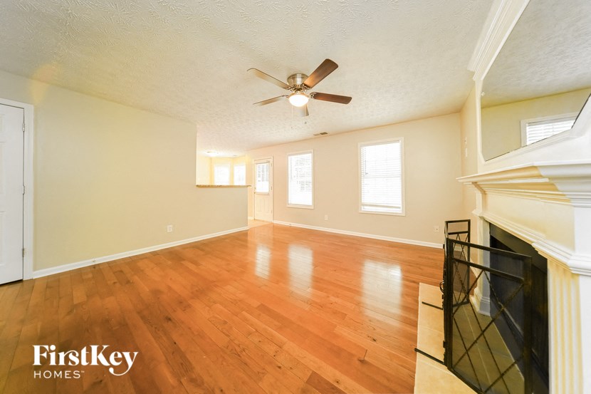 an empty living room with a fireplace and a ceiling fan